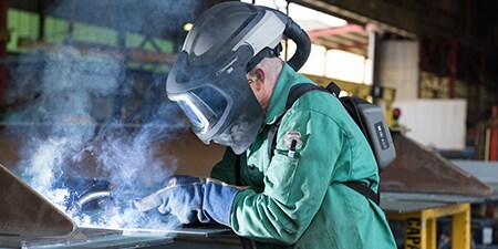 Welder wearing welding hood with PAPR
