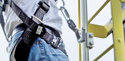 Worker climbing tower ladder connected to rigid rail ladder safety system

