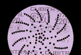 Disco de lixa 3M Cubitron II roxo com padrão espiral de furos para extração de poeiras e marcações impressas indicando a granulação e o produto.
