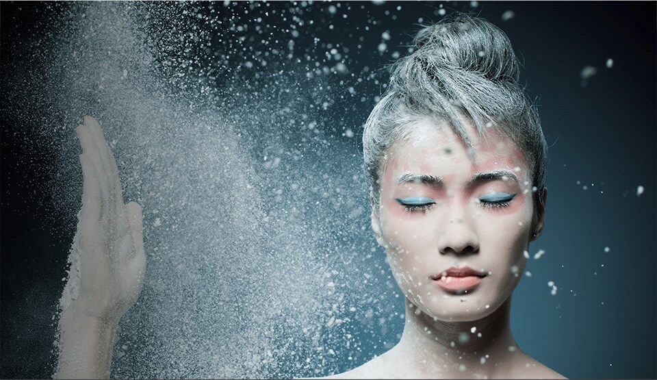 Portrait of a young adult woman with makeup explosively moving around her face, illustrating the dynamic nature of design.