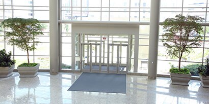 View of sliding doors and lobby of clean commercial building with many windows.
