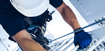 Worker climbing tower ladder using climb assist ladder system
