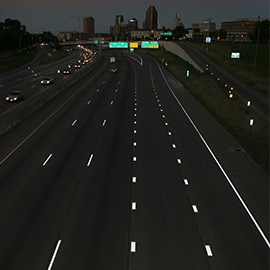 Foto noturna de uma rodovia vista de cima, com marcações rodoviárias apresentando alta refletividade.