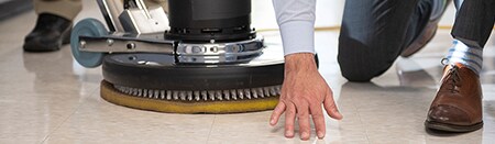 Funcionário inspecionando um piso de concreto revestido recentemente polido.
