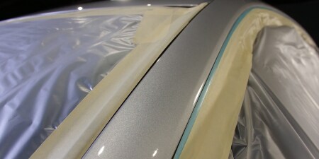 Image of masking film and masking tape applied over the windows of an automobile before the paint process
