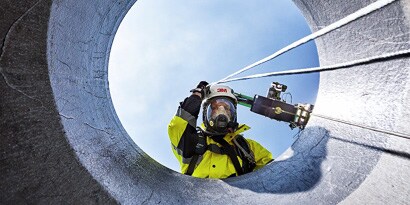 Worker wearing 3M Fall Protection looking down confined space access portal
