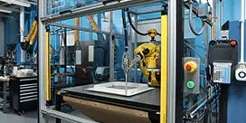 Uma máquina aplica adesivo em um produto.
