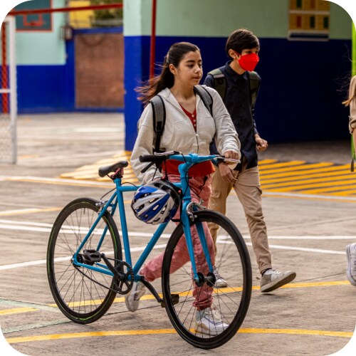 Girl wheeling her bike acrcoss shool grounds en route to class.
