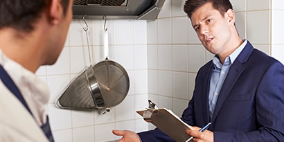 A smiling waiter serves food to four diners in a restaurant.
