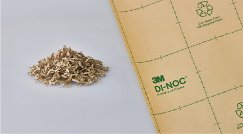 Pilha de papel reciclado ao lado de um rolo de filme arquitetônico 3M.

