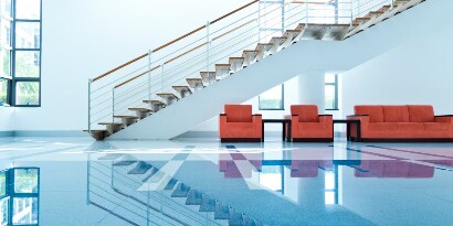 Saguão com piso limpo e brilhante, poltronas e sofás vermelhos e uma escada longa e moderna.
