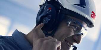Trabalhador usando comunicador 3M operando uma máquina
