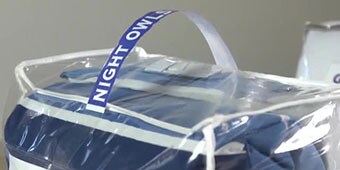 Image of a textile product in a plastic bag with a carry handle attached
