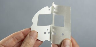 A hand peeling a liner off of a foam gasket

