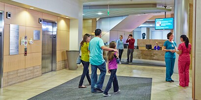 Família feliz caminhando por uma unidade de cuidados à saúde.
