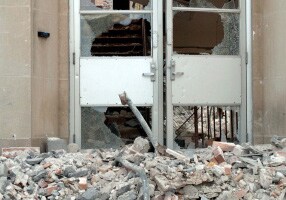Despite piles of debris outside a building, the glass doors remain intact.
