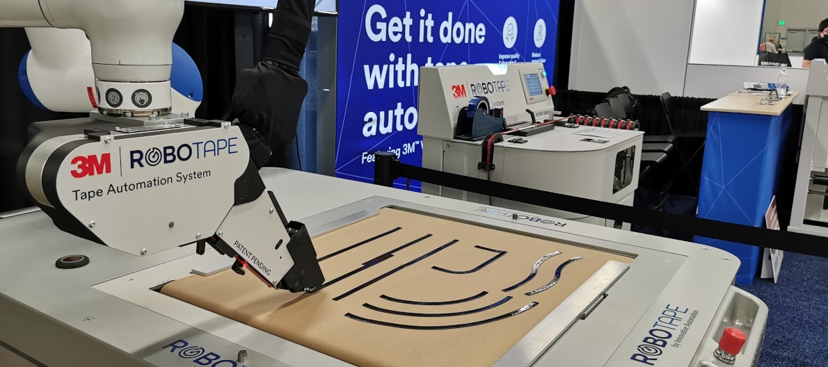 Image of two yellow robot arms, each with a RoboTape application head attached