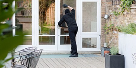 Uma pessoa tentando invadir uma casa pela janela.

