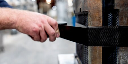 Image of a worker taping a bundle together on a job site
