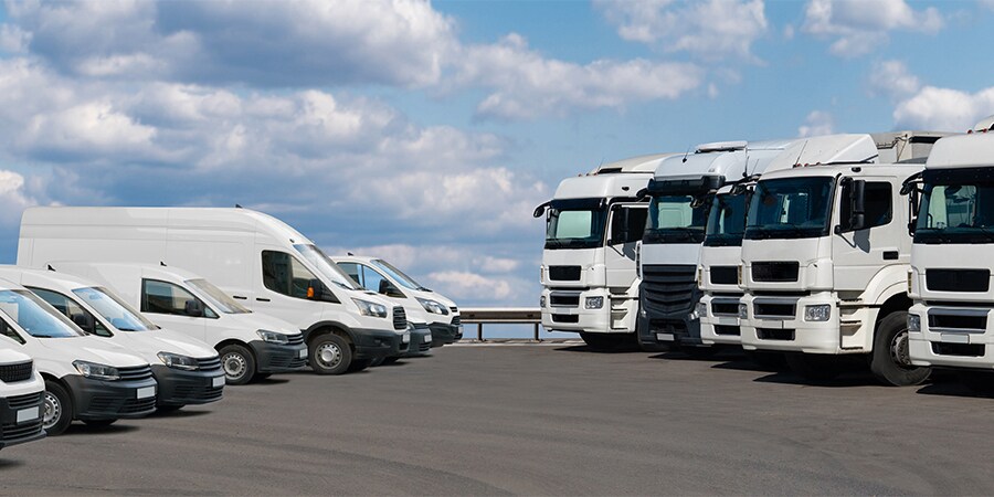 Frota comercial de caminhões e furgões estacionados.
