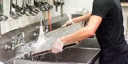 A man washing dishes in a commercial kitchen
