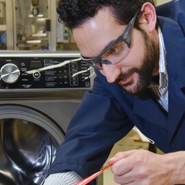 A person pulls a tape liner off of a washing machine