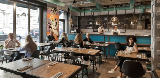 Quatro grupos de clientes sentados em um ambiente de restaurante moderno.
