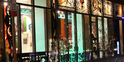 Uma fachada à noite com um interior iluminado e vitrines com gráficos de janela.
