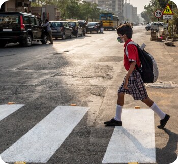 A young boy in a school uniform crossing at a crosswalk.
