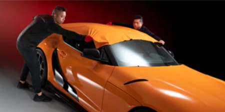 orange car wrap being installed by two installers

