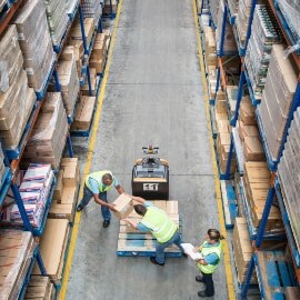Vista aérea de trabalhadores transferindo caixas de um palete para uma prateleira.