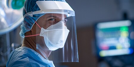 Clinician wearing a filtering facepiece respirator and faceshield during surgery
