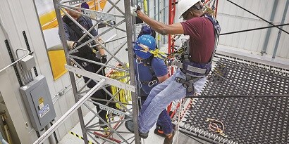Workers climbing up equipment in fall protection training facility
